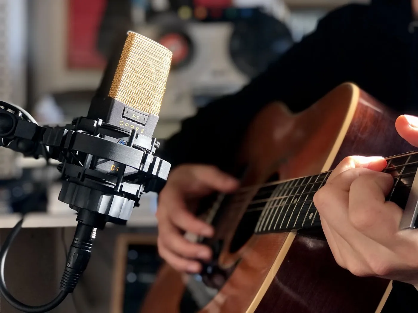 A vintage condenser microphone in front of an acoustic guitar